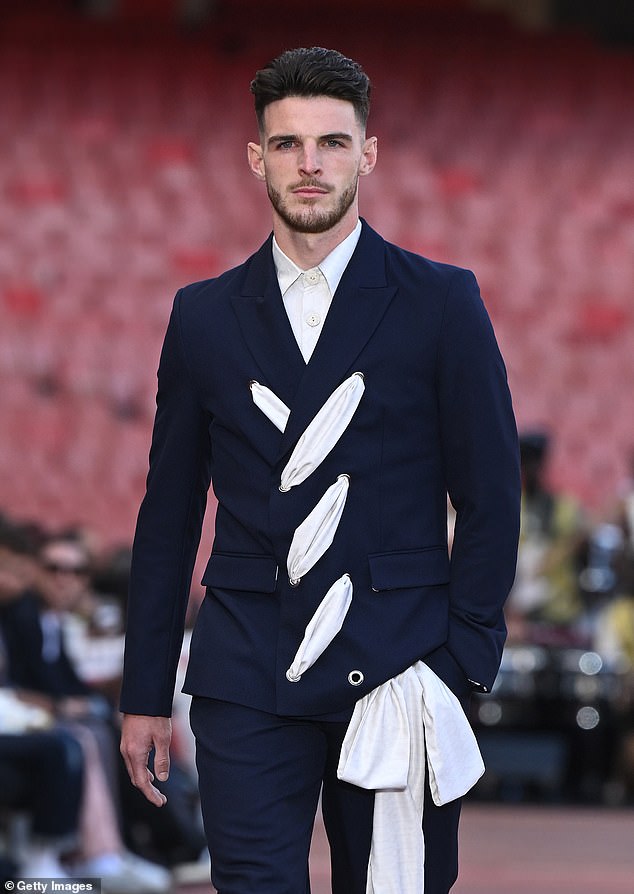 The Arsenal footballer, 25, looked every inch the perfect model as he walked his first fashion show in a navy jacket which boasted a white lace up tie down the front